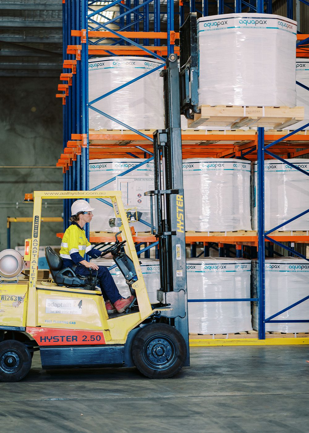 Woman driving forklift in warehouse filled with water pods